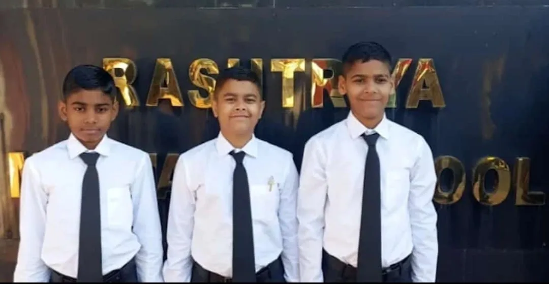Three Tejas students in white shirts and ties at the Rashtriya Military School sign